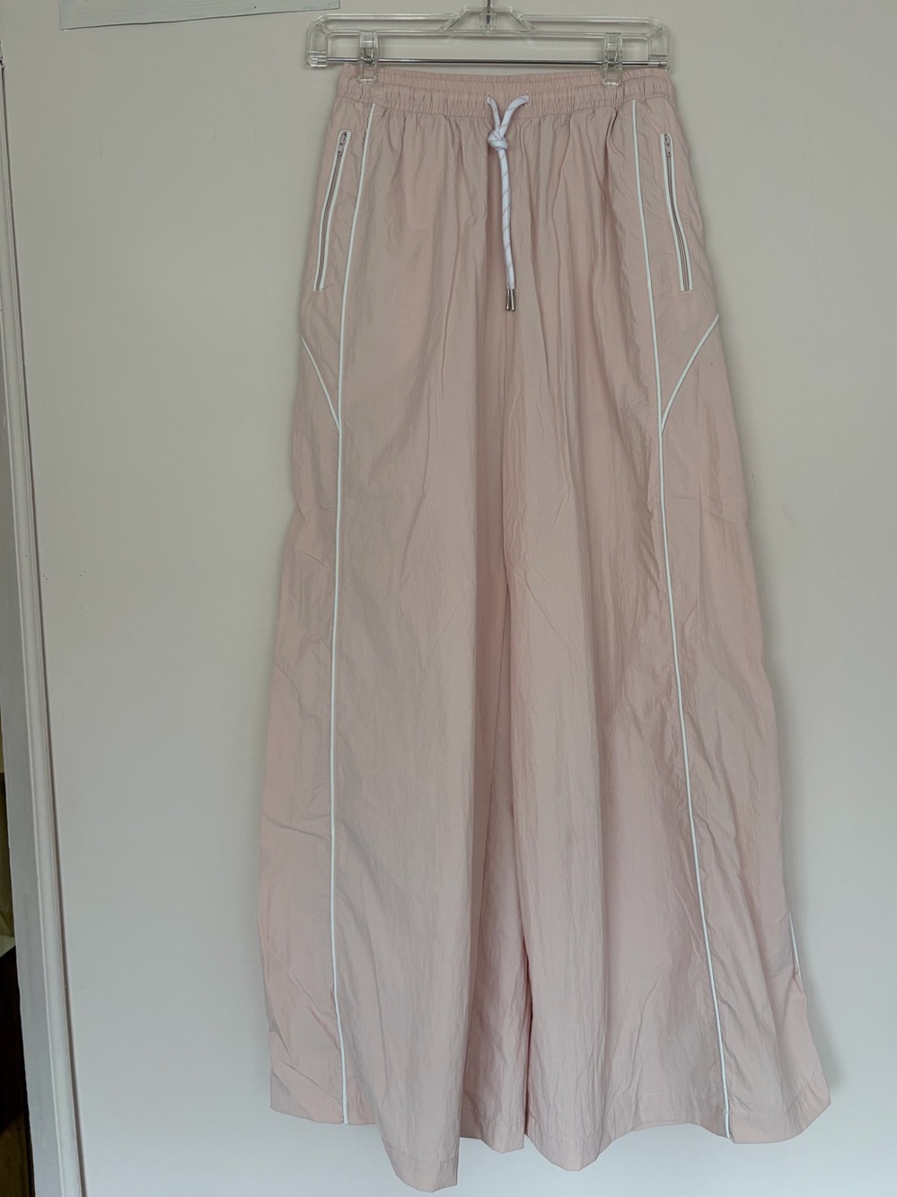 wide-leg nylon track pants featuring white piping, light pink